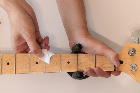 Close up of polishing a bass guitar neck and fretboard