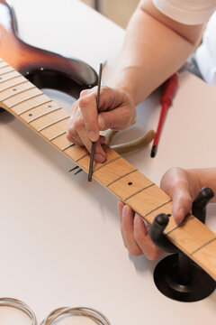 Applying conditioning oil to a bass guitar fretboard with a brush