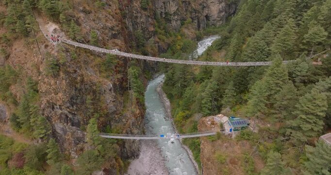 Everest region, Nepal, drone aerial shot of the iconic Hillary Suspension Bridge spanning across a deep rocky gorge above the rushing Dudh Koshi River.