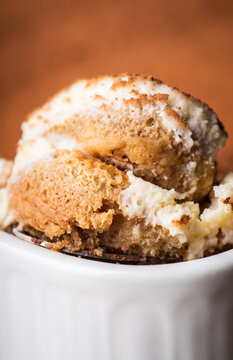 Creamy tiramisu in ceramic bowl being scooped with spoon. Cooking recipes. Selective focus.