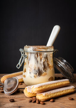 Empty tiramisu jar with spoon on rustic wooden background. Cooking recipes. Selective focus.