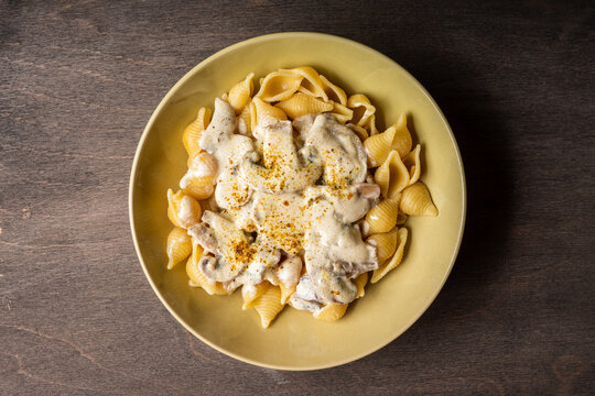 Homemade pasta with creamy mushroom sauce on dark wooden background. Shot from above.
