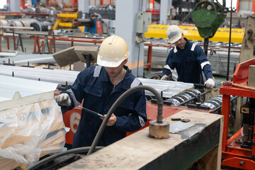 Fototapeta premium Factory workers inspecting metal sheets on production line, focused industrial teamwork in bright manufacturing plant