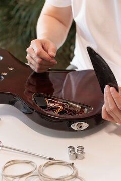 Hand lifting the electronics cover from an electric bass guitar