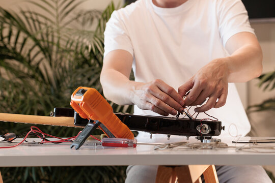 Repairman checking electric bass guitar wiring on a workbench