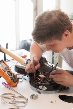 Young man testing bass guitar electronics with a digital multimeter