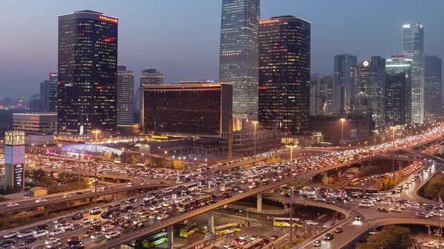  Day to night transition zoom out time Lapse at night of busy road intersection in Beijing's Soho financial district with traffic and commuters at rush hour