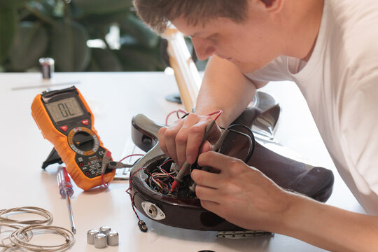 Man measuring electrical connections inside a bass guitar body