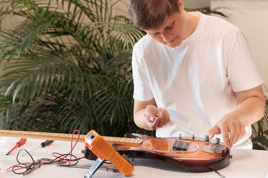 Man completing electric bass guitar repair by installing control knobs
