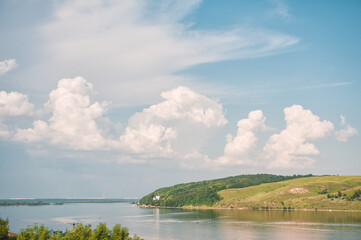 Naklejka premium Scenic river reflects cloudy sky. Peaceful landscape invites travel
