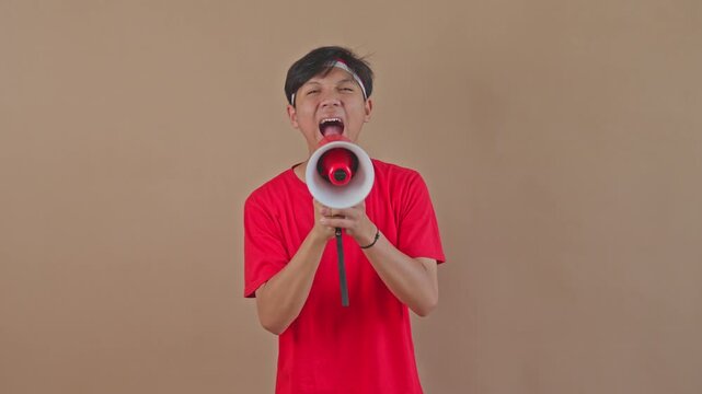 Excited Asian boy using megaphone to proclaim Independence Day news in studio