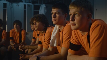 Fototapeta premium In Locker Room, Diverse Group of Teenage Boys Sits Absorbed in Theoretical Session With Mentor. Concept of Sport Education, Disciplined Listening, Development of Character Through Athletic Training.
