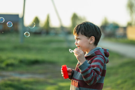 Happy person blowing soap bubbles outdoors in summer