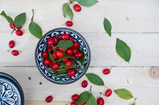 Bowl with leaves and fresh Cornelian cherries (Cornus mas)