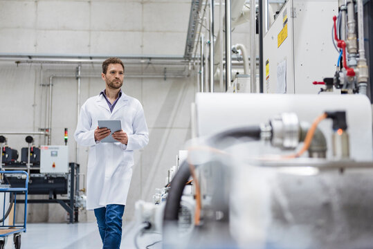 Employee checking manufacturing machines in high tech company, using digital tablet