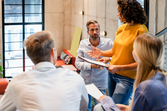 Businesswoman explaining over document to colleagues in office