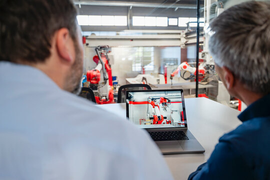 An engineer and colleague monitor an industrial robot indoors