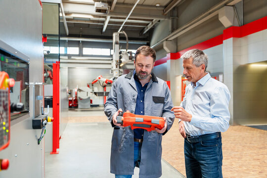 Manager and engineer inspect a remote control in a factory