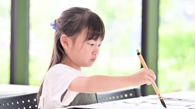 書道に集中して筆で文字を書く小学生の女の子・習字を学ぶ日本の子どものクローズアップの動画