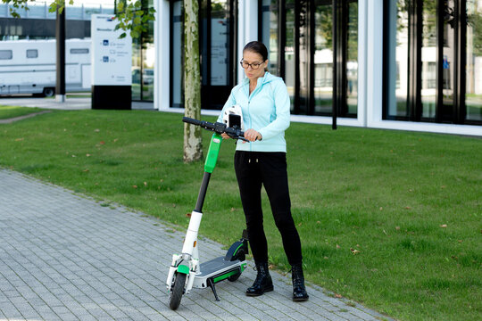 Mature woman scanning QR Code for activating rental electric scooter