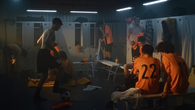 Youth Football Players Relax and Recover inside Warm, Atmospheric Locker Room After Match or Training Session. Teenage Soccer Team Changing Clothes, Talking, Preparing Gear in Modern Sports Facility.