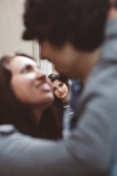 Young couple kissing with another woman looking at them