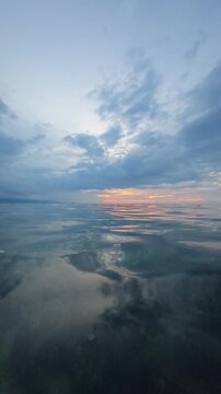 Slow Motion of Calm Ocean Reflecting Cloudy Sunset Sky 