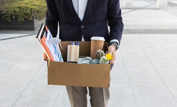 Businessman leaving office holding box with office supplies