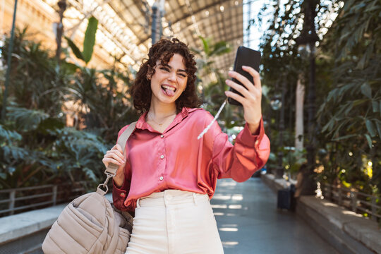 Woman sticking out tongue and taking selfie on smart phone