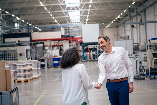 Happy businessman shaking hand with businesswoman in industry