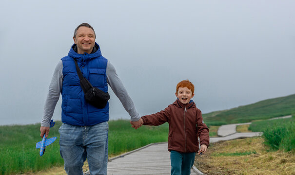 Happy father and son walk hand in hand on an outdoor path