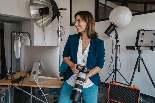 Smiling photographer holding camera in studio