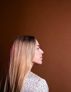 Profile portrait of a woman with blonde hair on brown background