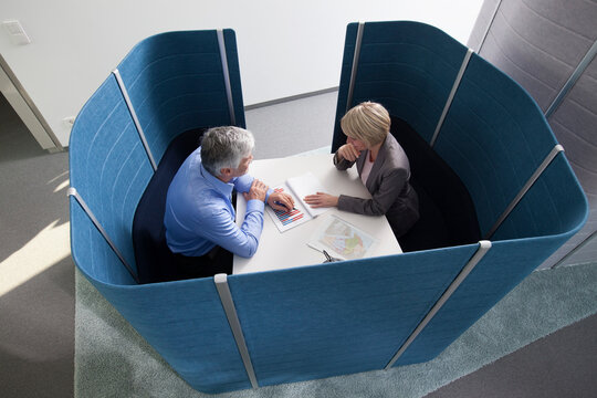 Businessman and businesswoman working in partitioned board room