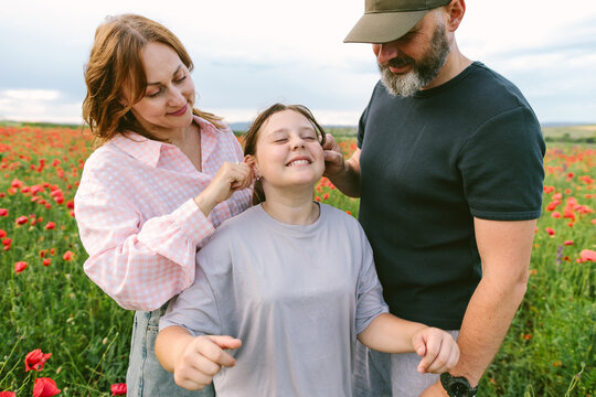 Mother and father playfully tease their daughter in a poppy field