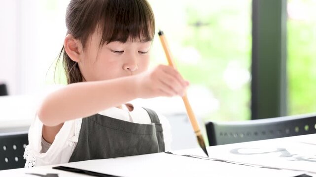 書道に集中して筆で文字を書く小学生の女の子・習字を学ぶ日本の子どものクローズアップの動画