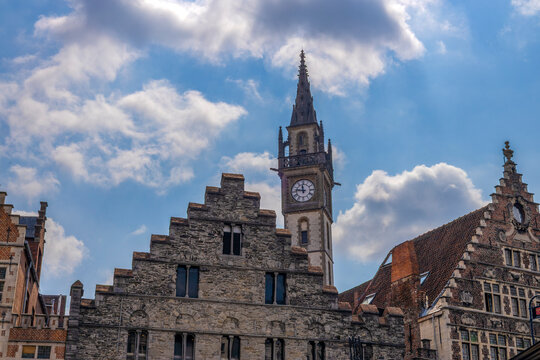 GHENT, BELGIUM, JULY 14, 2025 - The clock tower of the Former Post Office, rising behind the distinctive historic stone and brick facades that line the Graslei quay in Ghent, Belgium