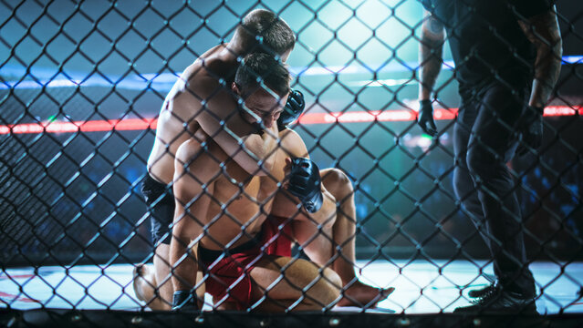 MMA Fighters Battle in a Ground Fight as One Locks a Rear Choke Submission From Back Control Inside the Cage. Referee Steps in to Watch the Finish, Fight for the Champion Title Belt.