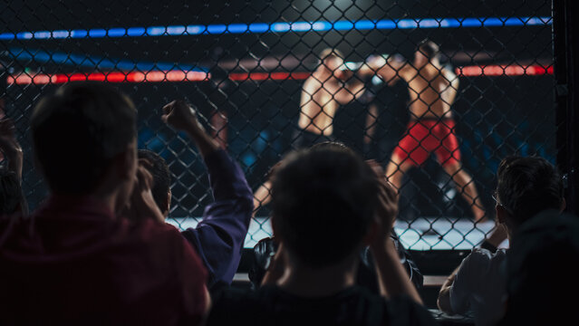 MMA Fighters Trade Punches and Kicks in a Fast Fight Inside the Cage During a Championship Title Show.  Competitive Martial Arts Battle for the Champion Win.