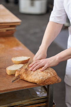 Professional baker slicing fresh rustic bread in a commercial bakery