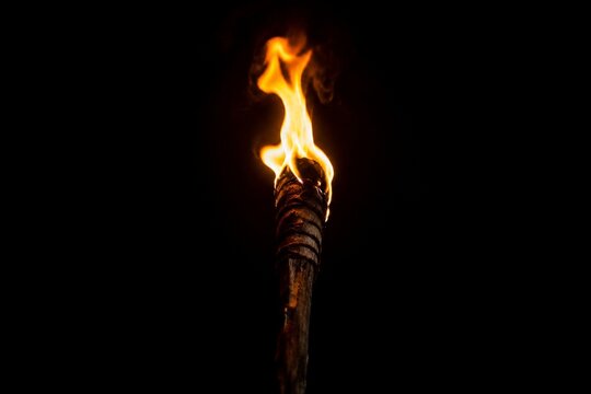 A single burning torch creating a focal point of light in darkness.