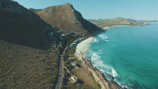 Aerial view of a coastal road winding through mountains to a beach