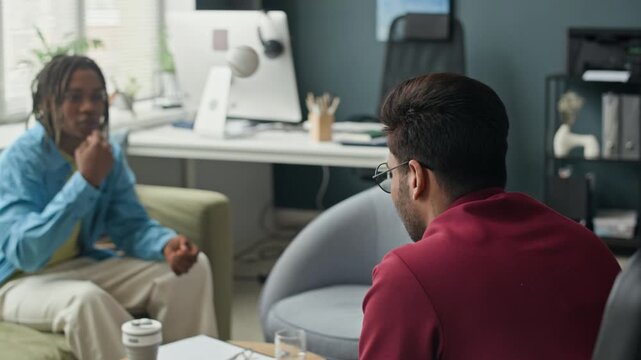 Diverse young adult colleagues, Indian and African American men, tossing baseball while talking in office. Footage suitable for corporate culture and team building content
