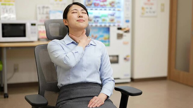 Japanese business woman suffering neck pain at desk, cinematic footage of female office worker massaging stiff muscles during work break in modern corporate interior
