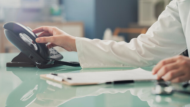 Doctor answering office phone at medical desk