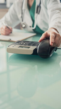 Doctor answering office phone at medical desk