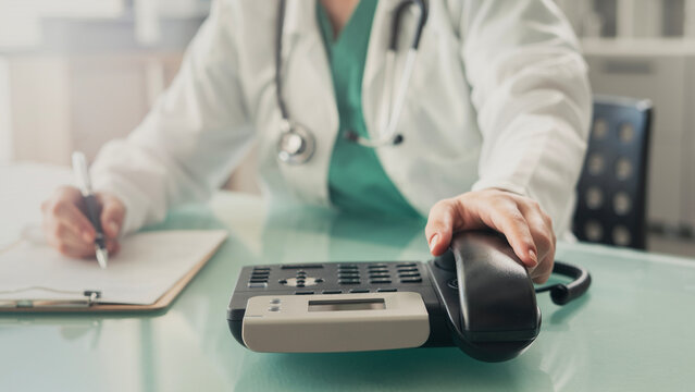 Doctor answering office phone at medical desk