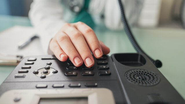 Doctor answering office phone at medical desk