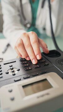 Doctor answering office phone at medical desk