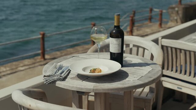 Seaside dining setup with wine and a plate of food on weathered table